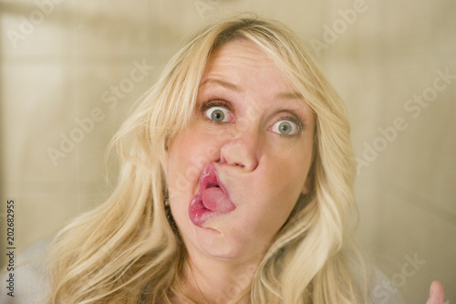 Foto Blonde woman smashing face against window silly look