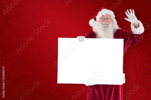 Santa holds a sign and is waving against red background © vectorfusionart