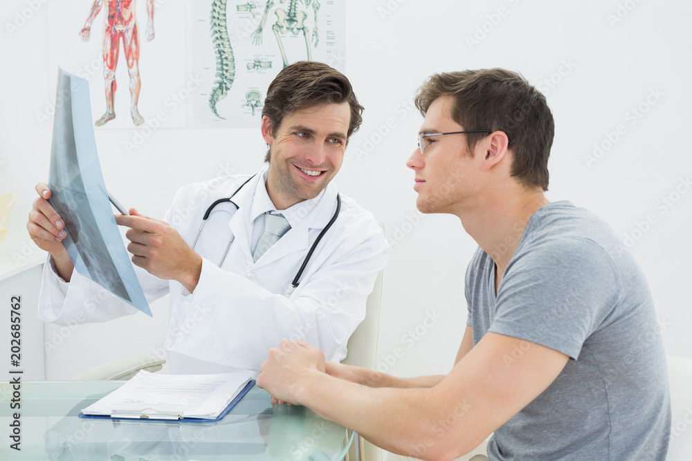 Smiling male doctor explaining spine xray to patient Smiling male doctor explaining spine xray to patient