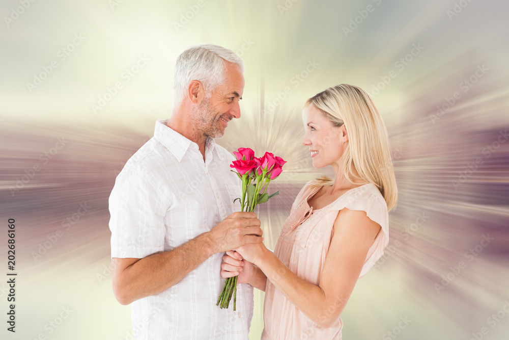 Affectionate man offering his partner roses against room with large window looking on city Affectionate man offering his partner roses against room with large window looking on city