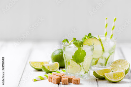 Summer refreshing cocktail caipirinha with lime and mint on white wooden vintage background.