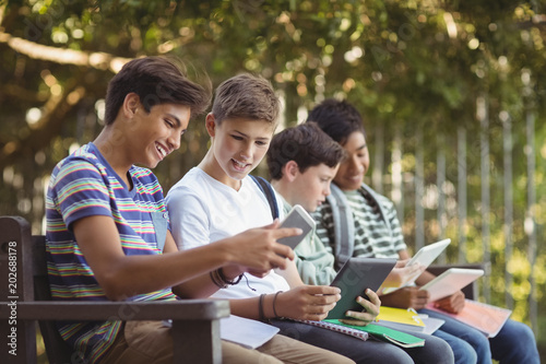 School kids using mobile phone and digital tablet on bench © WavebreakmediaMicro