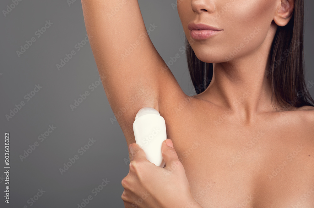 Close up of young girl doing hygienic procedure. She applying antiperspirant on armpit. Copy space in left side. Isolated on background Close up of young girl doing hygienic procedure. She applying antiperspirant on armpit. Copy space in left side. Isolated on background