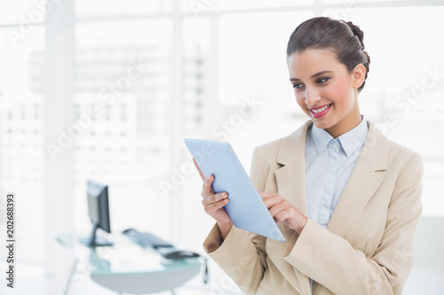 Pleased smart brown haired businesswoman using a tablet pc