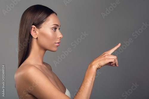 Profile of beautiful girl touching something pleasant with her finger. Copy space in right side. Isolated on background photo