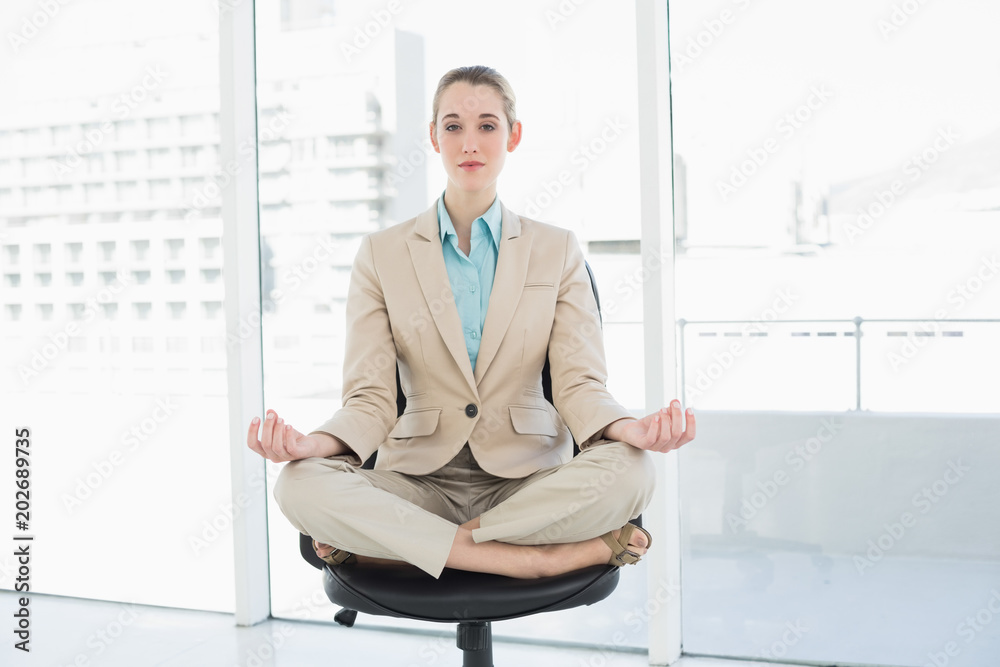 Lovely chic businesswoman sitting in lotus position on her swivel chair Lovely chic businesswoman sitting in lotus position on her swivel chair