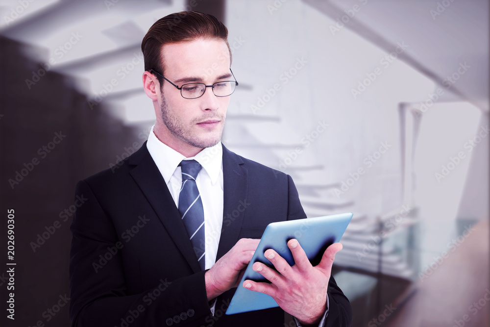 Unsmiling businessman using tablet pc against stylish modern home interior with staircase Unsmiling businessman using tablet pc against stylish modern home interior with staircase