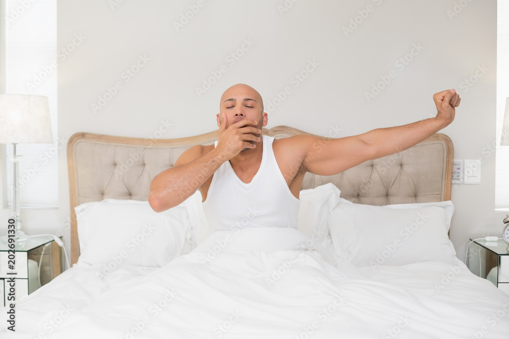 Man waking up in bed and stretching his arms Man waking up in bed and stretching his arms