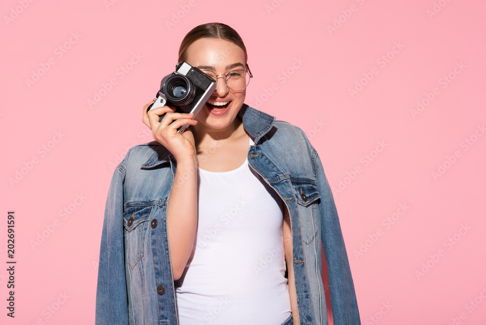 Smile. Waist up portrait of excited girl taking photo and smiling. Isolated on pink background Smile. Waist up portrait of excited girl taking photo and smiling. Isolated on pink background
