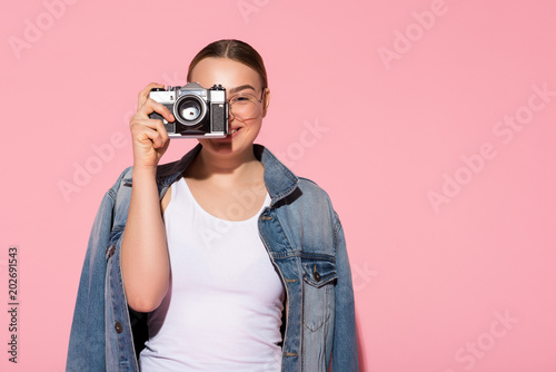 Portrait of inspired female photographer making snap with joy. She is standing and laughing. Copy space