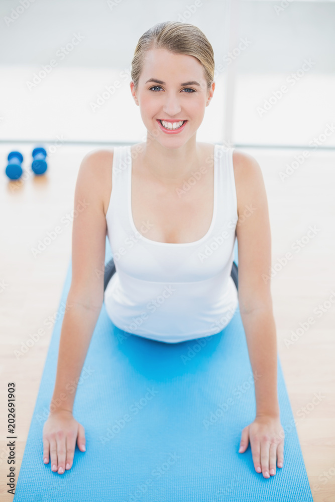 Smiling fit woman stretching on sport mat