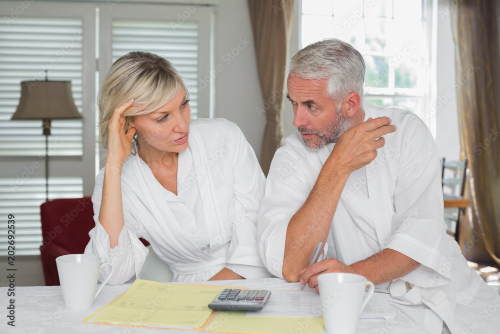 Couple sitting with home bills and calculator Couple sitting with home bills and calculator