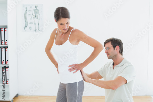 Physiotherapist examining womans back in medical office