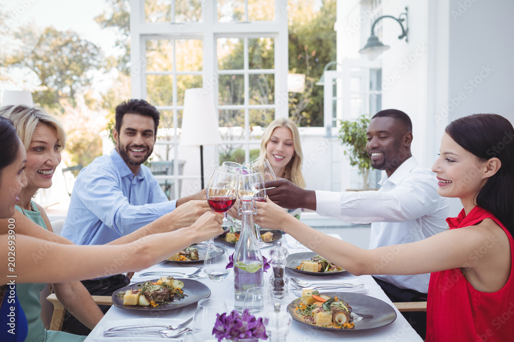 Group of friends toasting glasses of wine during meal Group of friends toasting glasses of wine during meal