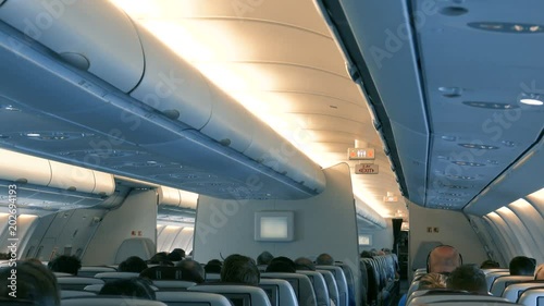 Interior of a big airplane cabin with a lot of passengers 
