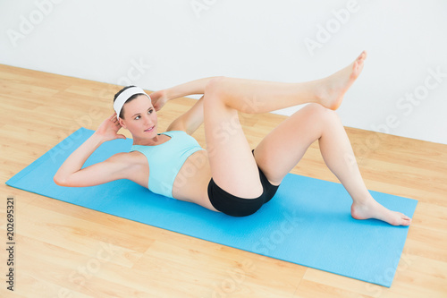 Sporty fit woman doing sit ups on exercise mat