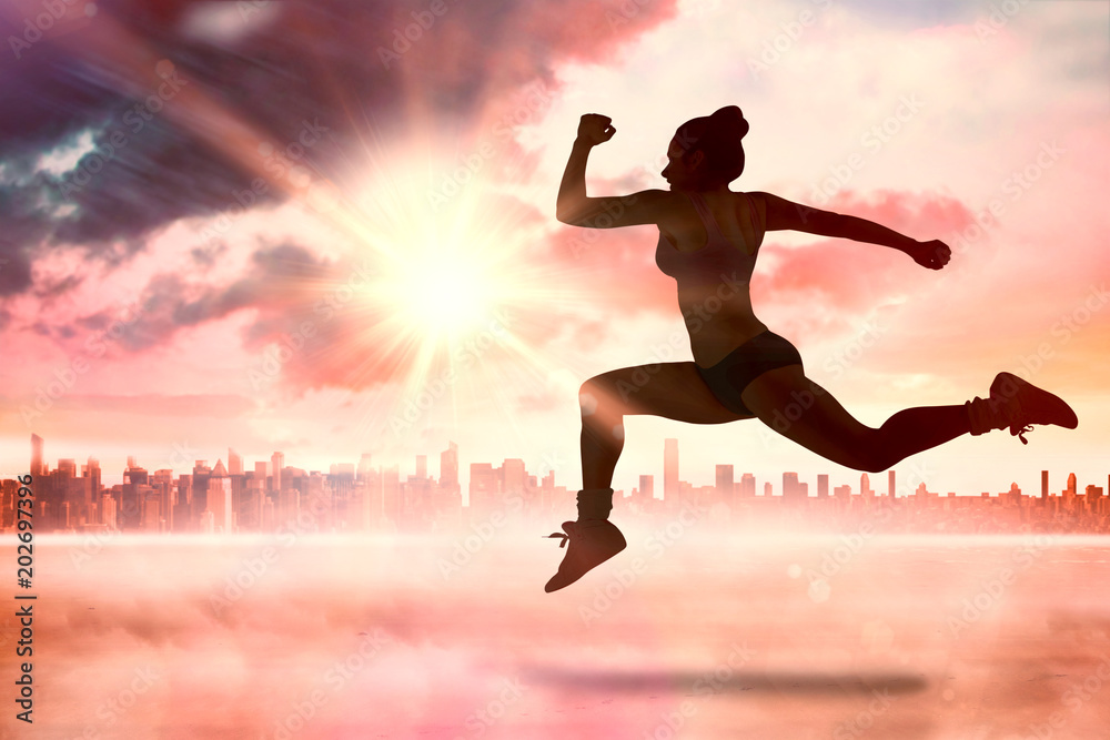 Fit brunette running and jumping against sun shining over city Fit brunette running and jumping against sun shining over city