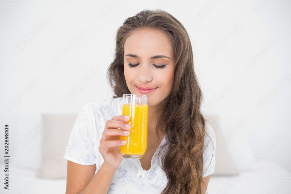 Content attractive brunette holding a glass of orange juice Content attractive brunette holding a glass of orange juice