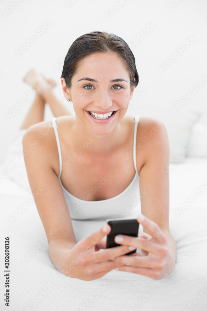 Portrait of a smiling woman with mobile phone in bed Portrait of a smiling woman with mobile phone in bed