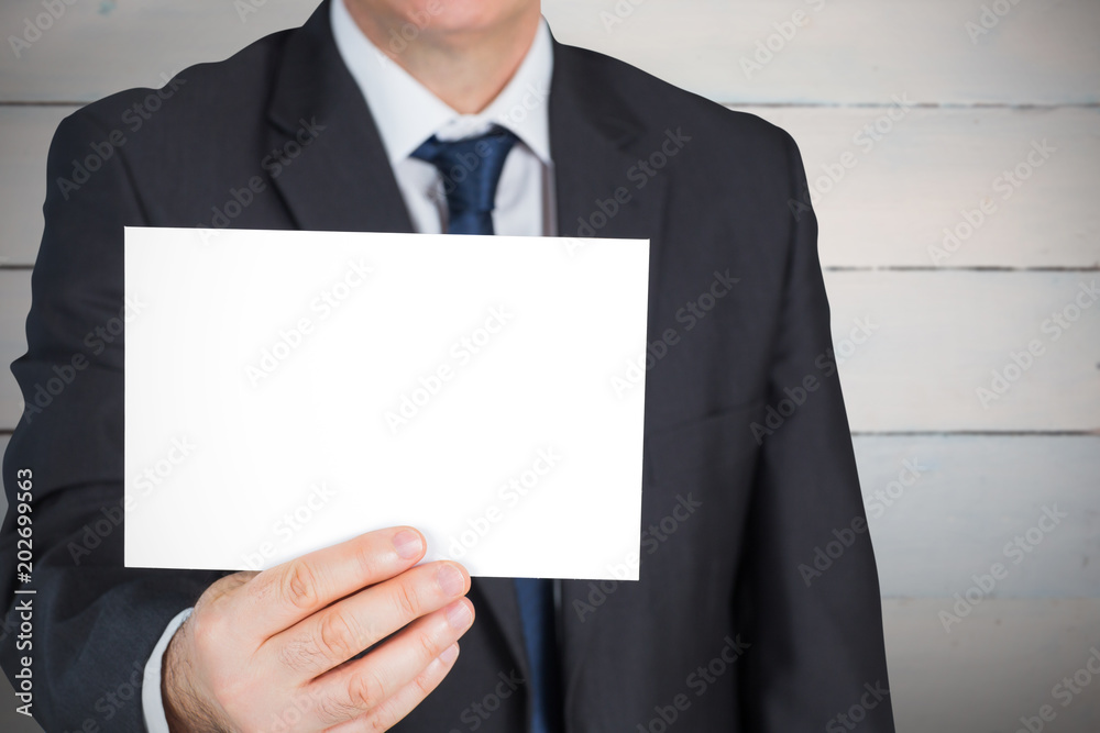 Mature businessman showing card against painted blue wooden planks Mature businessman showing card against painted blue wooden planks