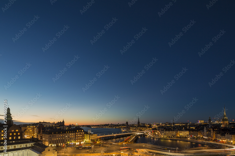 Motion blurred light tracks of highway traffic to Old city (Gamla Stan) cityscape pier architecture with historic town houses in Stockholm, Sweden. Creative long time exposure landscape photography