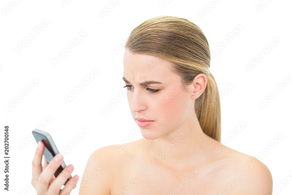 Frowning attractive blonde looking at her smartphone Frowning attractive blonde looking at her smartphone
