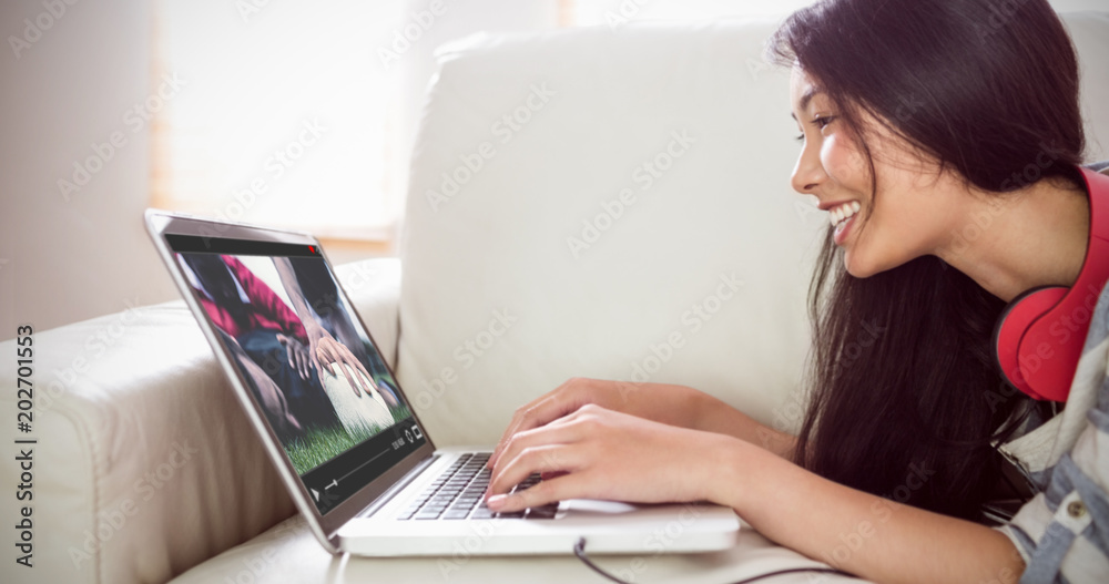 View of lecture app against smiling asian woman on couch using laptop View of lecture app against smiling asian woman on couch using laptop