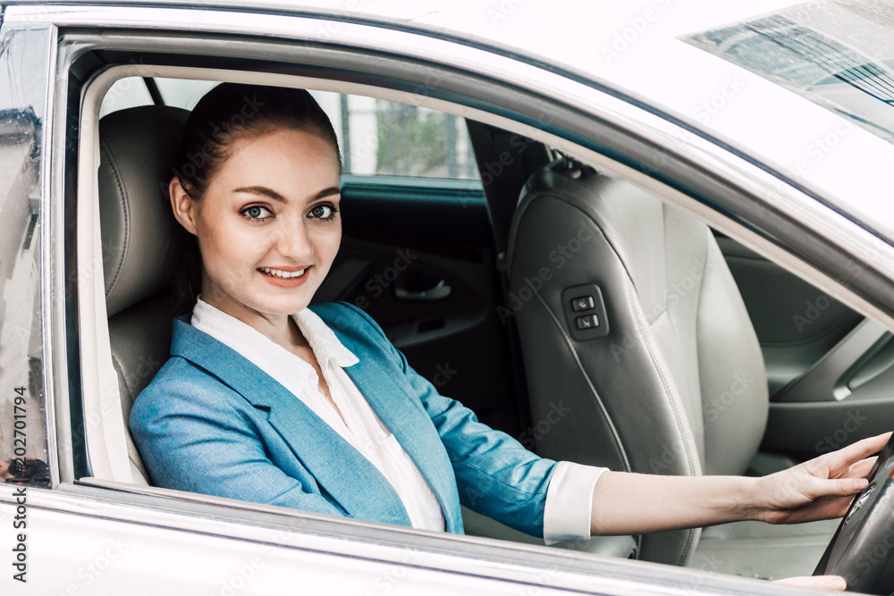 Businesswoman driving her car with smiling and looking at camera on the way to office