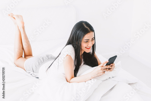 Happy woman relaxing and using smartphone on the bed at home.woman checking social apps with smartphone