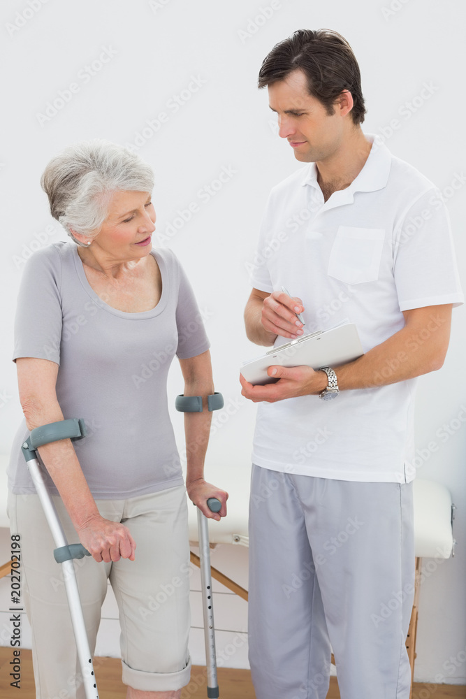Therapist discussing reports with a disabled senior patient Therapist discussing reports with a disabled senior patient