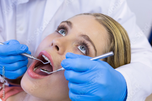 Dentist examining a female patient with tools