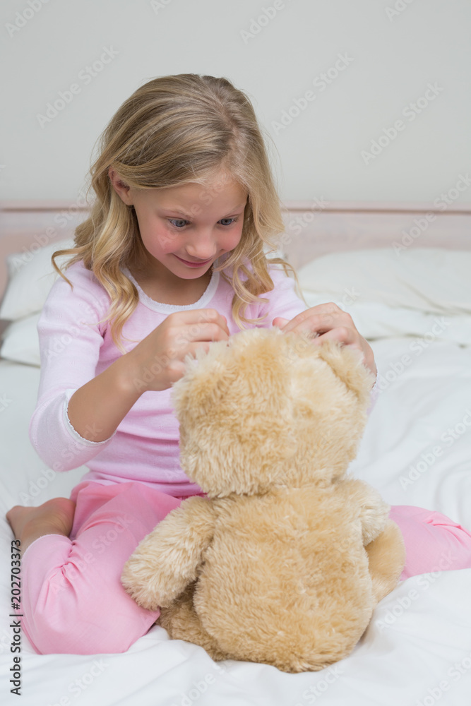 Relaxed girl sitting with stuffed toy in bed