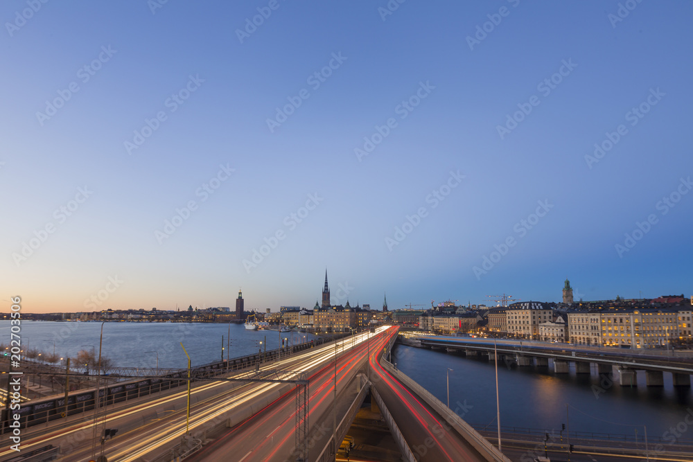 Motion blurred light tracks of highway traffic to Old city (Gamla Stan) cityscape pier architecture with historic town houses in Stockholm, Sweden. Creative long time exposure landscape photography