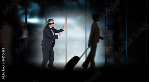 Mature businessman in a blindfold against room with large window looking on city