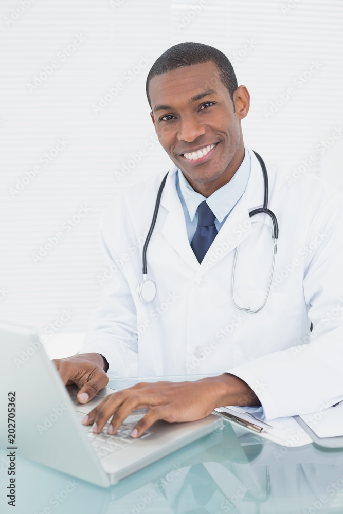 Smiling doctor using laptop at medical office Smiling doctor using laptop at medical office