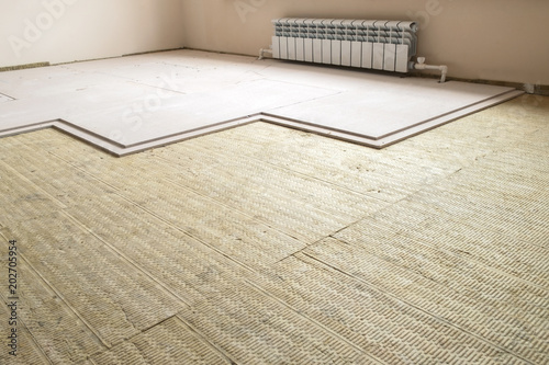 Thermal and sound protection in the interior of the apartment. Mounting of the protective system of stone wool and gypsum panels on the floor of the room.