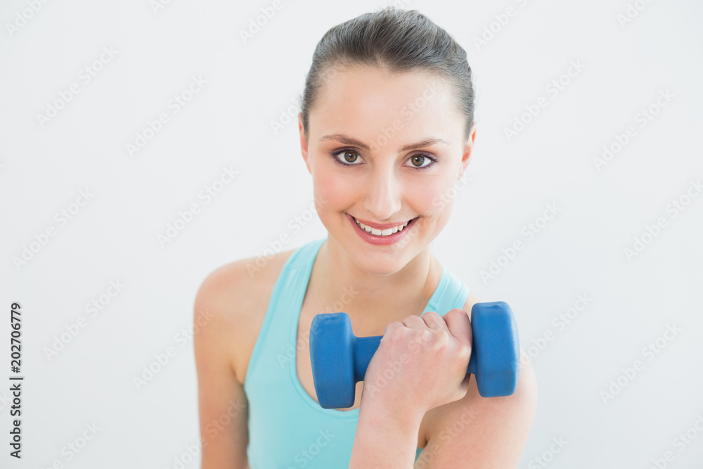 Portrait of woman with dumbbell against wall Portrait of woman with dumbbell against wall