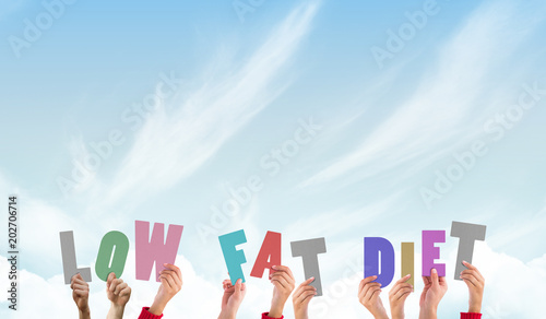 Hands holding up low fat diet against blue sky