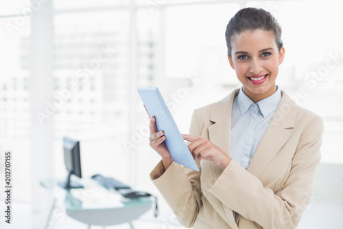 Cheerful smart brown haired businesswoman using a tablet pc