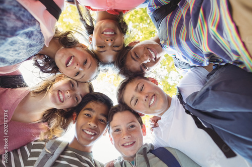 Portrait of smiling school kids forming a huddle in campus photo