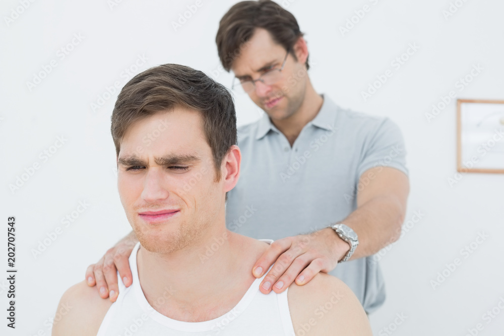 Fototapeta premium Male physiotherapist massaging a young mans shoulder