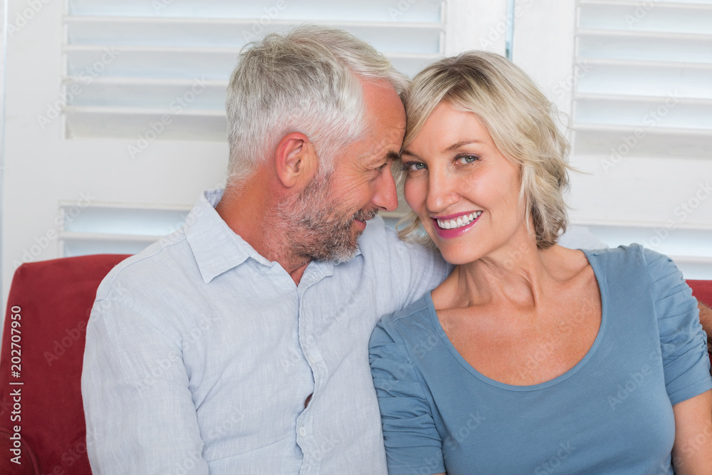 Smiling mature couple sitting on couch Smiling mature couple sitting on couch