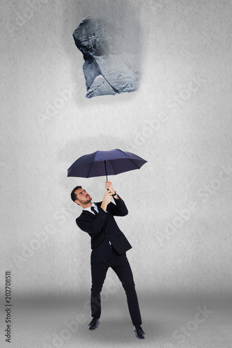 Businessman standing under black umbrella against grey room