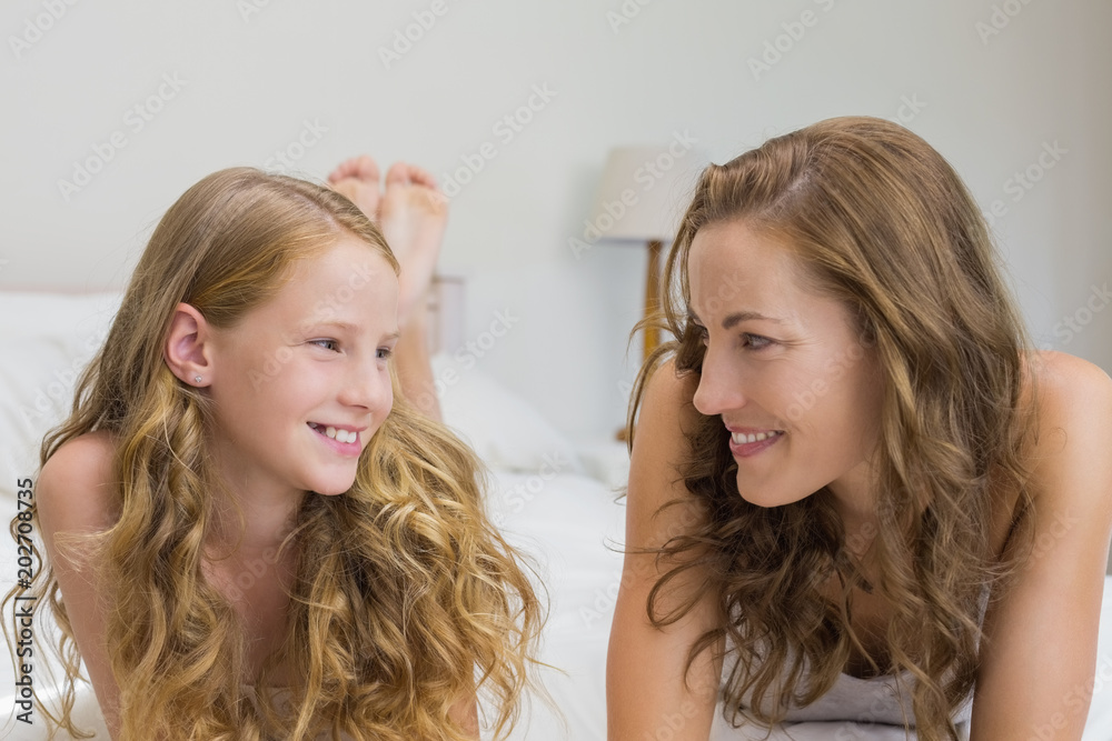 Smiling mother and daughter lying in bed Smiling mother and daughter lying in bed
