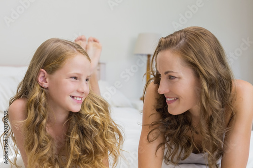 Smiling mother and daughter lying in bed