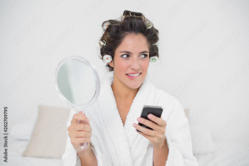 Pensive natural brunette holding mirror and smartphone Pensive natural brunette holding mirror and smartphone