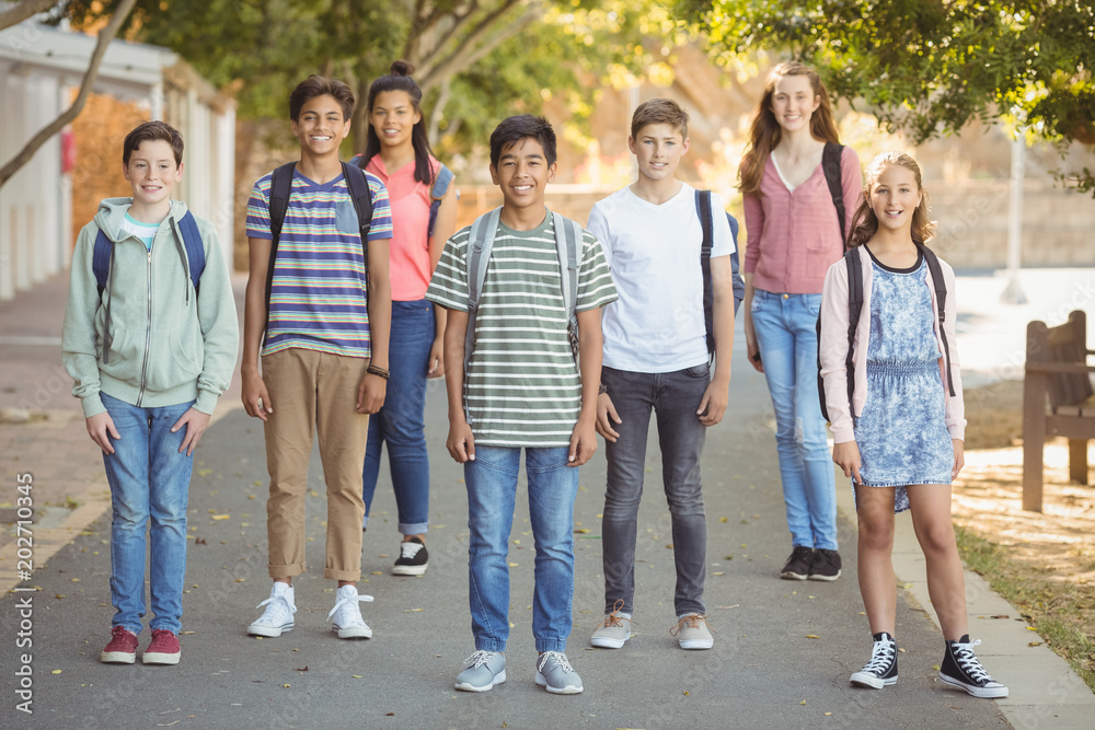 Portrait of happy students standing with schoolbag on road Portrait of happy students standing with schoolbag on road