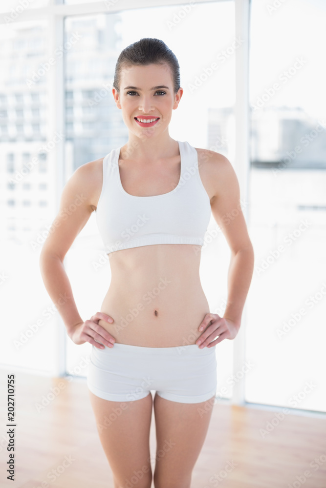 Pleased fit brown haired model in sportswear posing with hands on the hips
