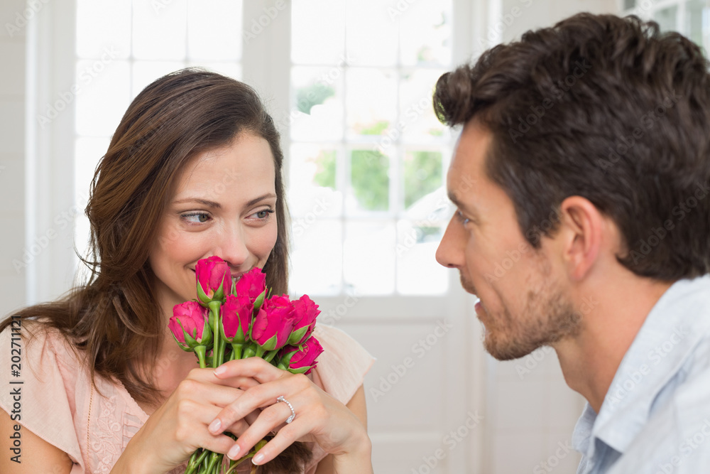 Woman looking at man with flowers at home Woman looking at man with flowers at home