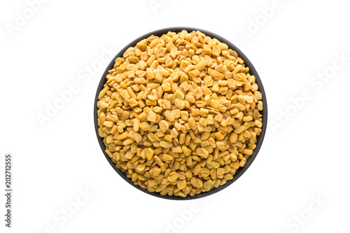 fenugreek seed in clay bowl isolated on white background. Seasoning or spice top view